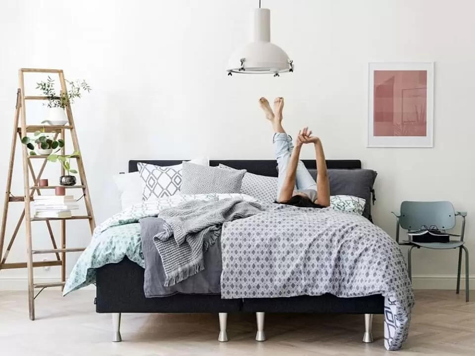 Sypialnia w stylu skandynawskim z wzorzystą bawełnianą pościelą, poduszkami i narzutą.