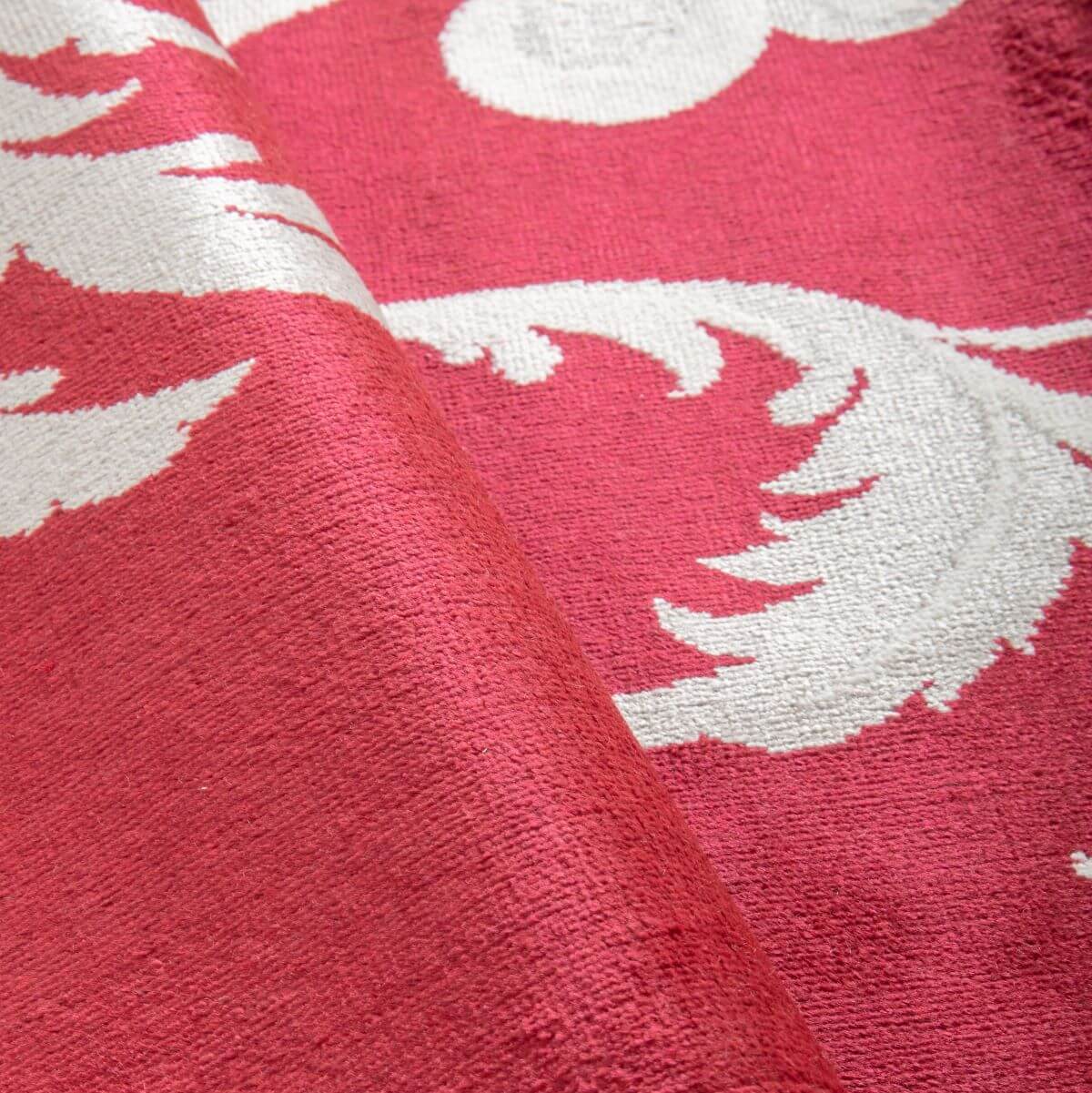 Fragment złożonego czerwonego dywanu w ornament FANFAARI z krótkim włosiem. Elegancki dywan do salonu w biało szare kwiaty z połyskiem wiskozy