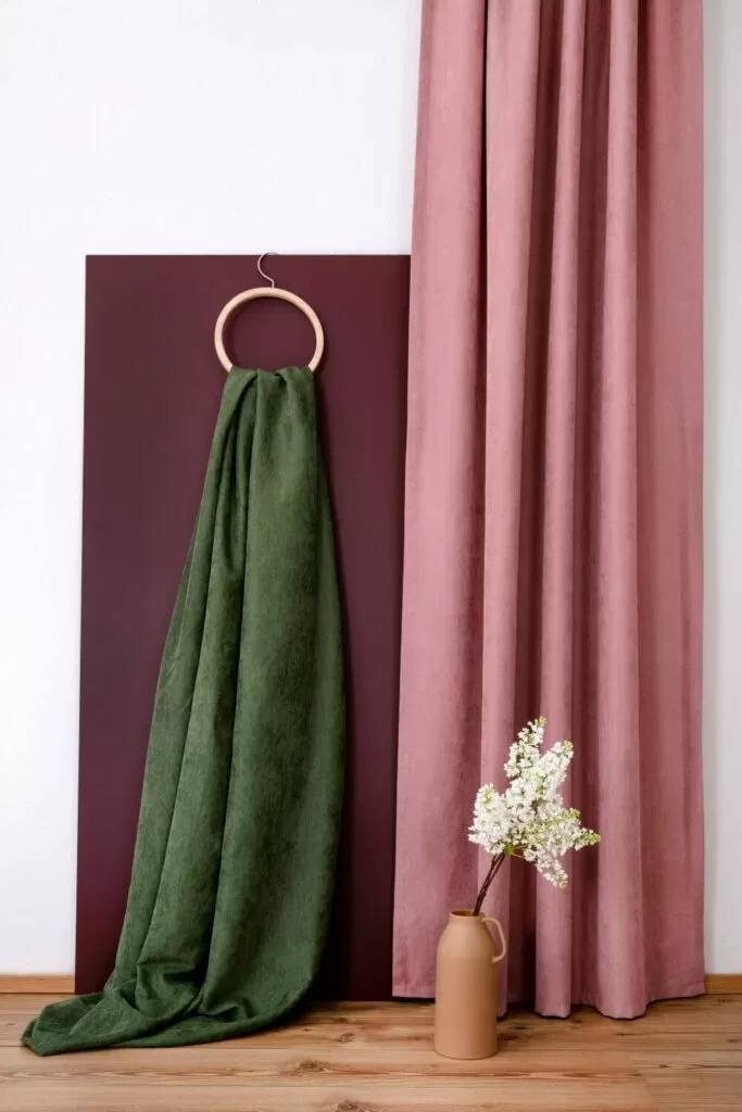 Różowe i zielone zasłony do modnego salonu. Połączenie przygaszonego różu i zieleni pięknie komponuje się z szarymi ścianami.