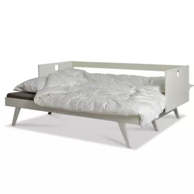 Rozłożona nowoczesna sofa z drewnianymi bokami NOTTE z beżowym materacem i pościelą. Sofa rozkładana na wysokich nóżkach z brzozy skandynawskiej lakierowanej na kolor biały