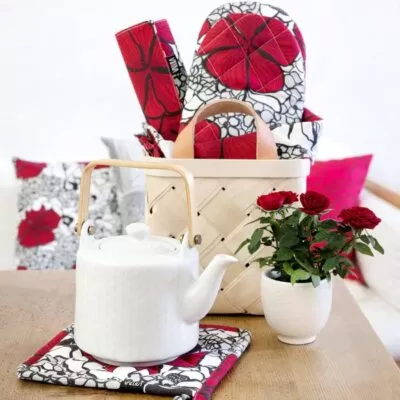 Wzór ELLE w splecione eleganckie czerwone i drobne szare kwiaty na białym tle na tekstyliach kuchennych firmy Vallila. Aranżacja na skandynawskim stole