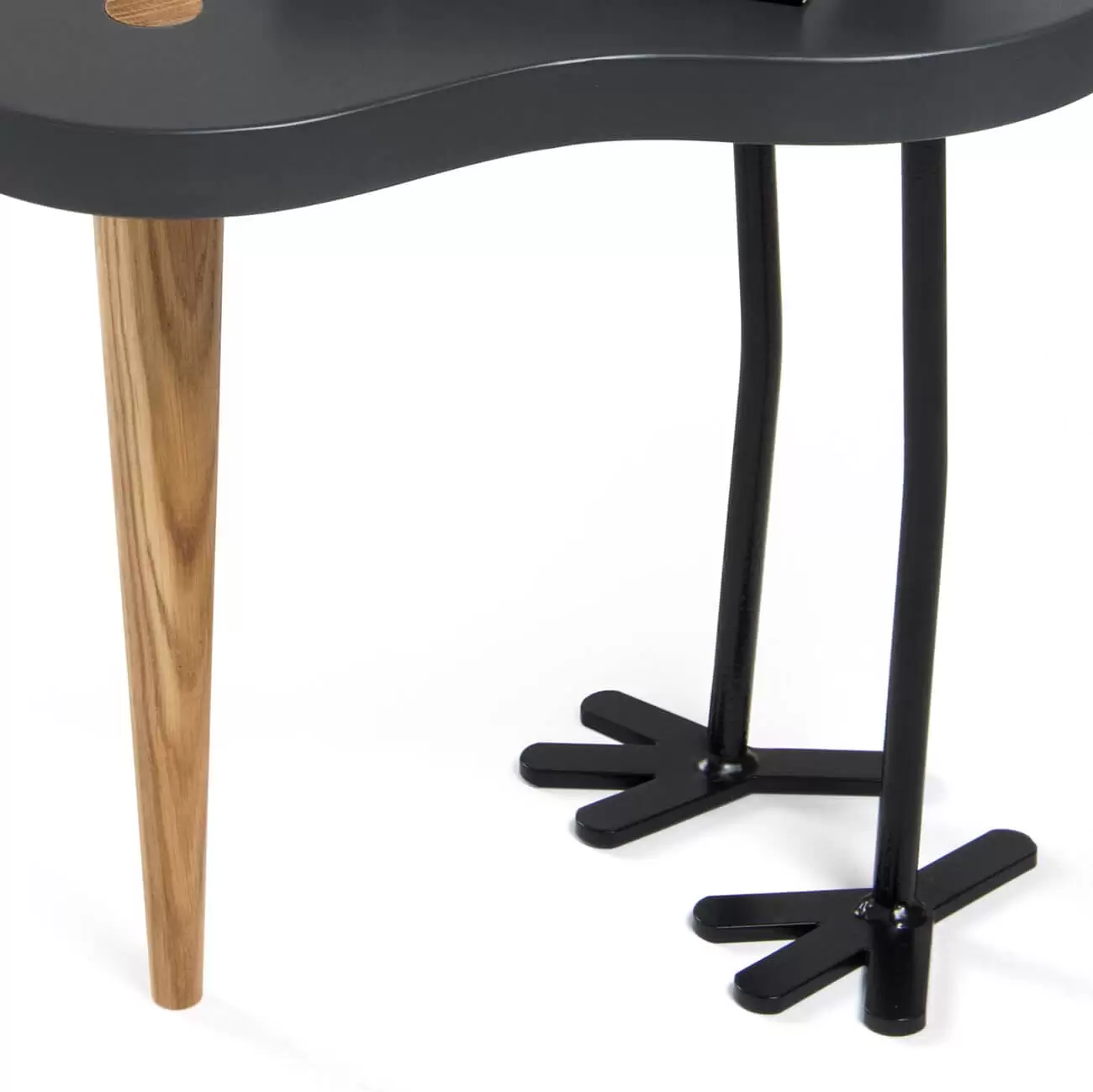 Dekopracyjny stolik ze zbliżeniem dębowej nogi i metalowych, czarnych nóg.