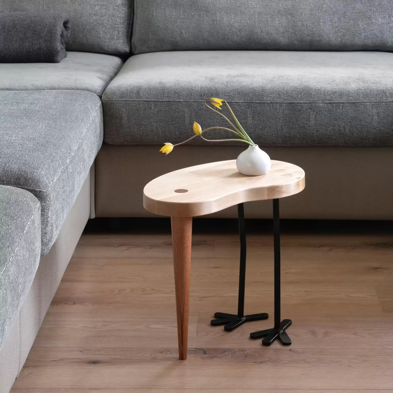 Designerski stolki kawowy z grubym blatem z brzozy skandynawskiej w kolorze naturalnym drewna. Podparty nogą z mahoniu i dwoma nogami z metalu w kolorze czarnym.