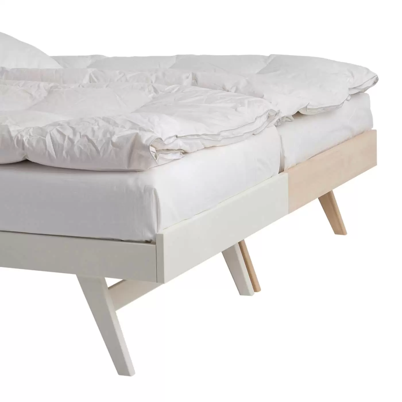 Łóżko na nóżkach NOTTE. Przybliżony fragment widoku na wysokie skośne nóżki złączonych, stojące razem obok siebie łóżek. Jedno łóżko z drewna brzozy, drugie z drewna brzozy lakierowanej na kolor biały