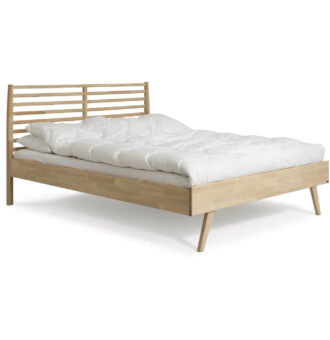 Łóżko drewniane 160x200 NOTTE. Widoczne w całości łóżko z drewna na wysokich nóżkach, z ażurowym zagłówkiem z litego drewna brzozy skandynawskiej i leżąca biała kołdrą. Nowoczesny design