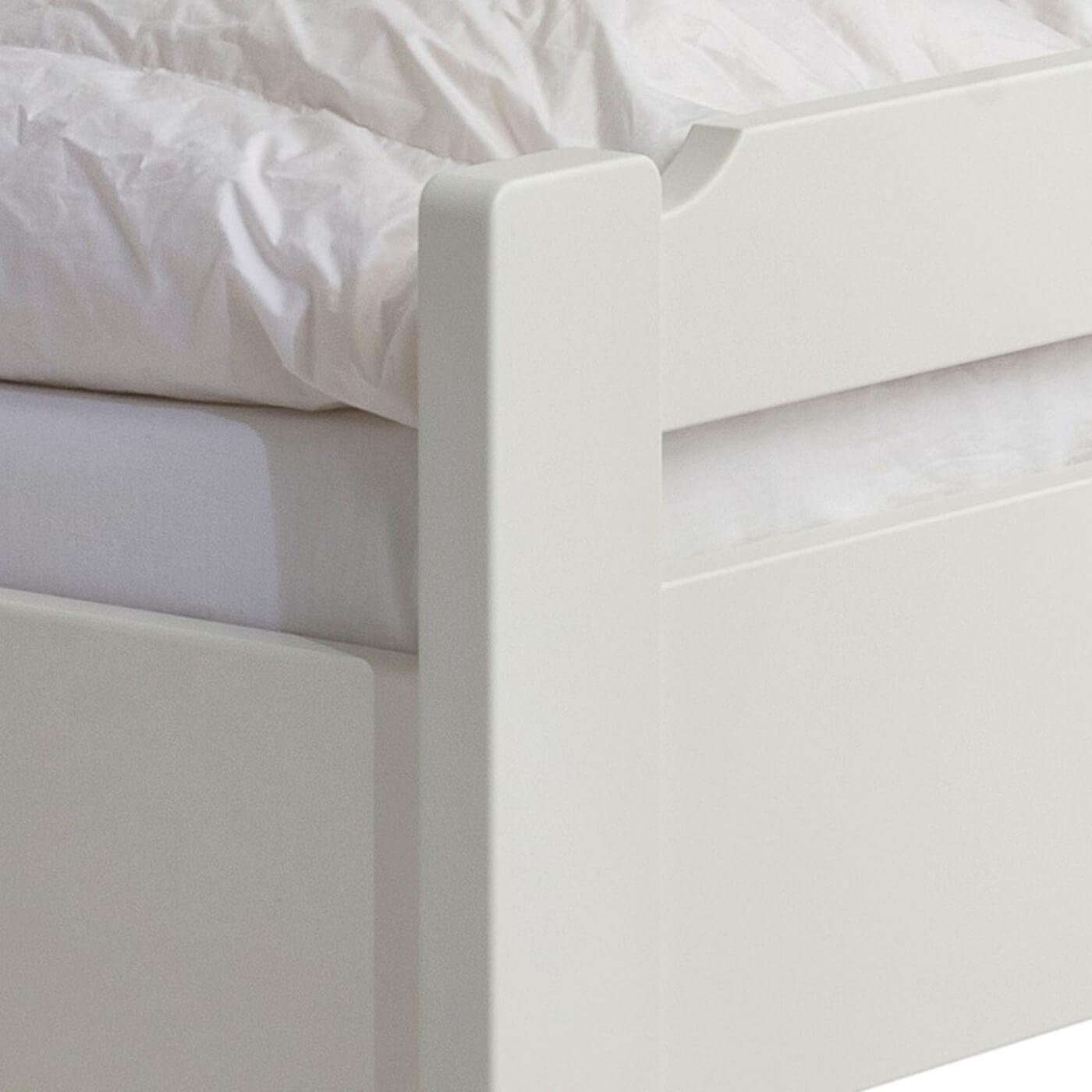 Łóżko jednoosobowe białe KUUSAMO. Zbliżenie na ręcznie robiony fragment prostego niskiego wezgłowia z litego drewna brzozy skandynawskiej lakierowanej na kolor biały mat