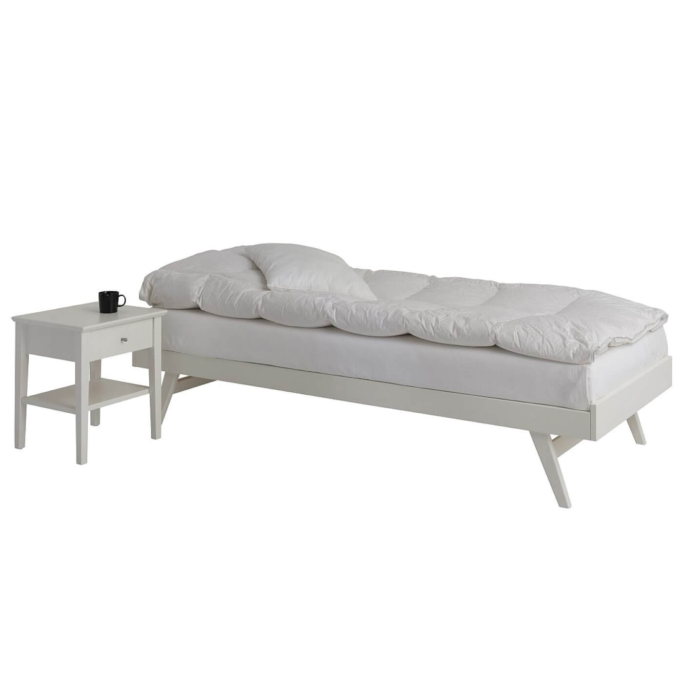 Łóżko na nóżkach NOTTE białe z materacem, białą kołdrą i poduszka widoczne w całości. Obok stoi biały stolik nocny z czarnym kubkiem. Skandynawski design