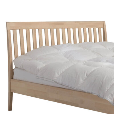 Łóżko z drewnianym zagłówkiem MATINEA. Przybliżony fragment łóżka 160x200 do sypialni z drewna brzozy z dużym i wysokim ażurowym zagłówkiem i leżącą białą kołdrą. Nowoczesny skandynawski design