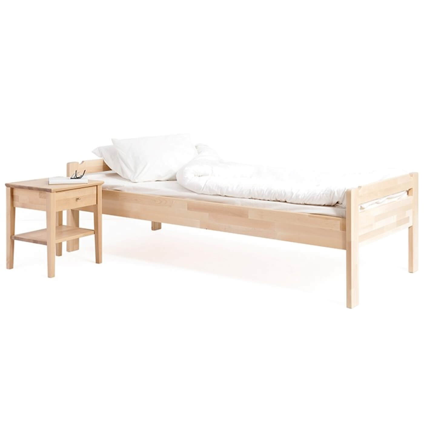 Łóżko z niskim zagłówkiem KUUSAMO z materacem 90x200, białą kołdrą i poduszką. Łóżko na wysokich prostych nóżkach widoczne w całości razem ze stolikiem nocnym drewnianym. Na stoliku leży książka i okulary. Skandynawski design