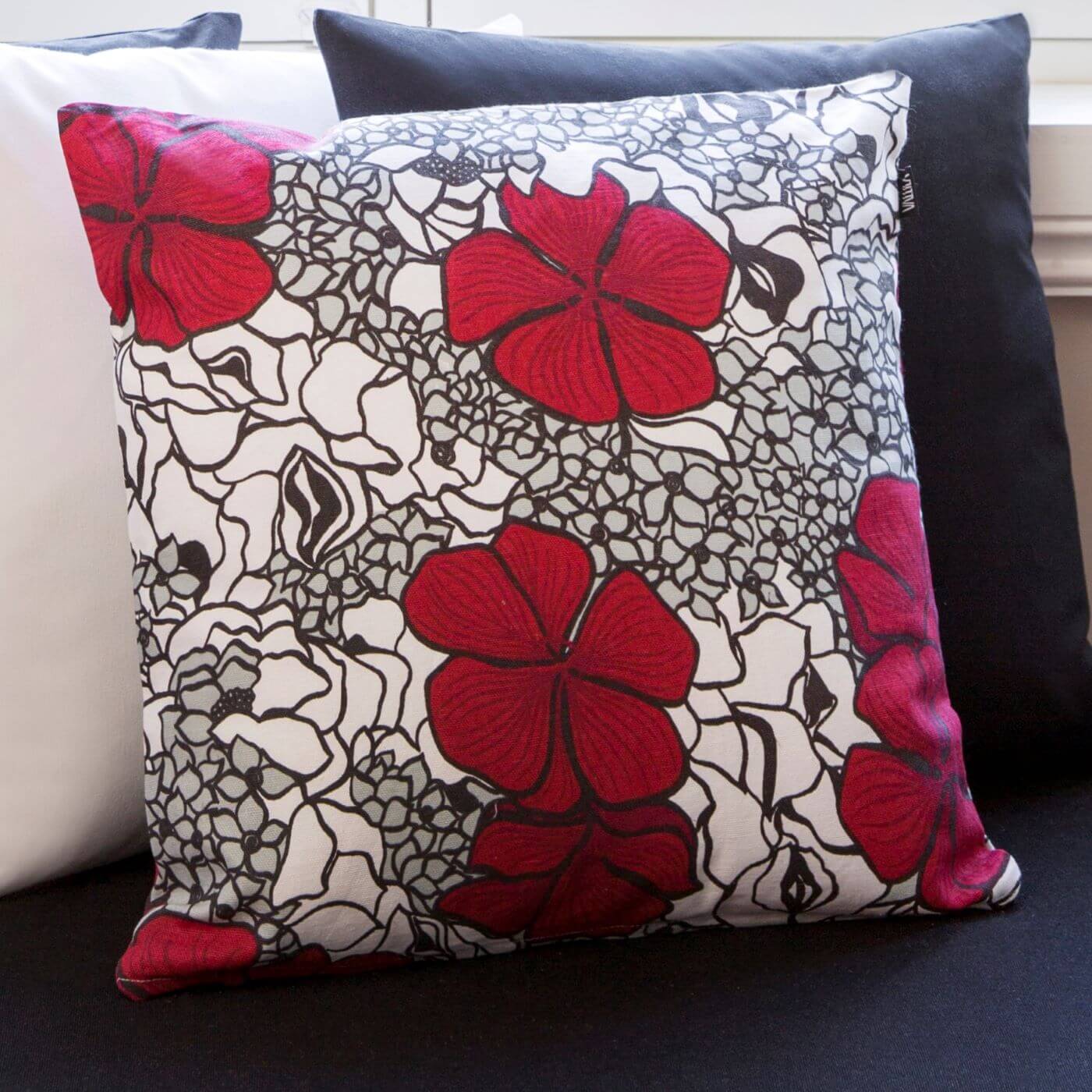 Poduszka dekoracyjna czerwone kwiaty ELLE. Bawełniana poduszka ze wzorem w splecione eleganckie czerwone i drobne szare kwiaty na tle innych poduszek dekoracyjnych. Skandynawski nowoczesny design