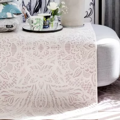 Dywanik biało różowy ALEKSANDRA. Stylowy różowy dywanik w biały wzór jak koronka do sypialni lub salonu w zbliżeniu aranżacji na szarej sofie skandynawskiej z dekoracyjnymi poduszkami