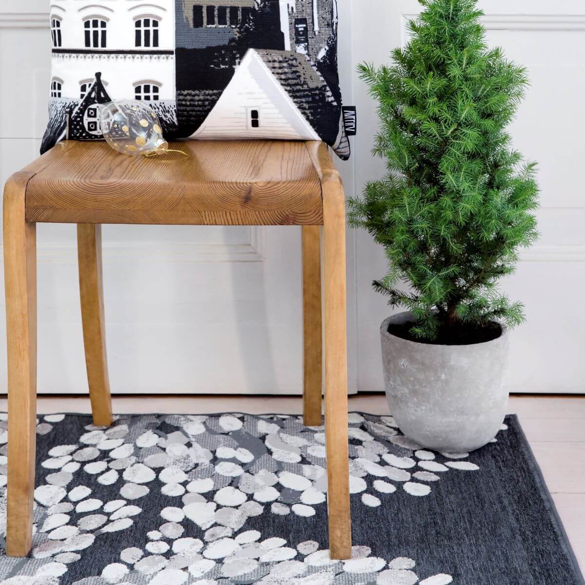 Dywan szary nowoczesny SYDÄNPUU. Leżący na podłodze szary dywan wzór 3d w aranżacji w salonie skandynawskim z drewnianym krzesłem, poduszką dekoracyjną i choinką